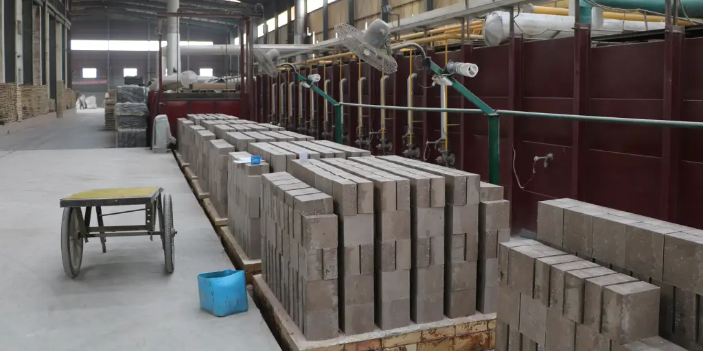 Formed green blocks of magnesia iron spinel refractory bricks aligned neatly before entering the high-temperature tunnel kiln.